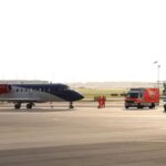Imagen de una azafata de KLM en un avión, con un fondo de hospital en Ámsterdam