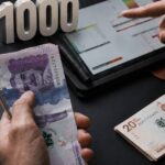 Una persona sostiene una tarjeta de débito con una expresión de frustración, con un fondo de dinero y una ciudad colombiana