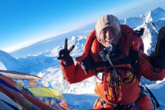 Purnima Shrestha en la cima del Everest con una vista impresionante de los picos nevados