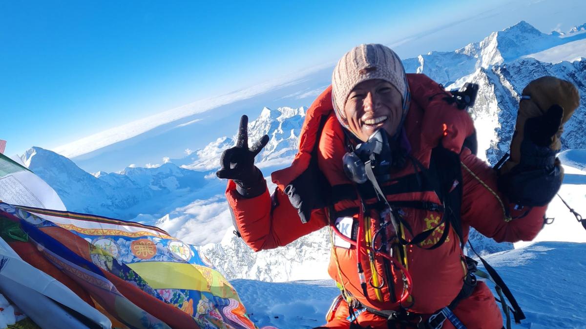 Purnima Shrestha en la cima del Everest con una vista impresionante de los picos nevados