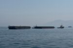 Barcos en el estrecho de Ormuz con bandera de Irán al fondo