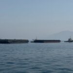 Barcos en el estrecho de Ormuz con bandera de Irán al fondo
