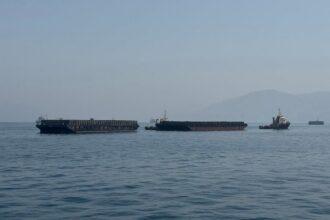 Barcos en el estrecho de Ormuz con bandera de Irán al fondo