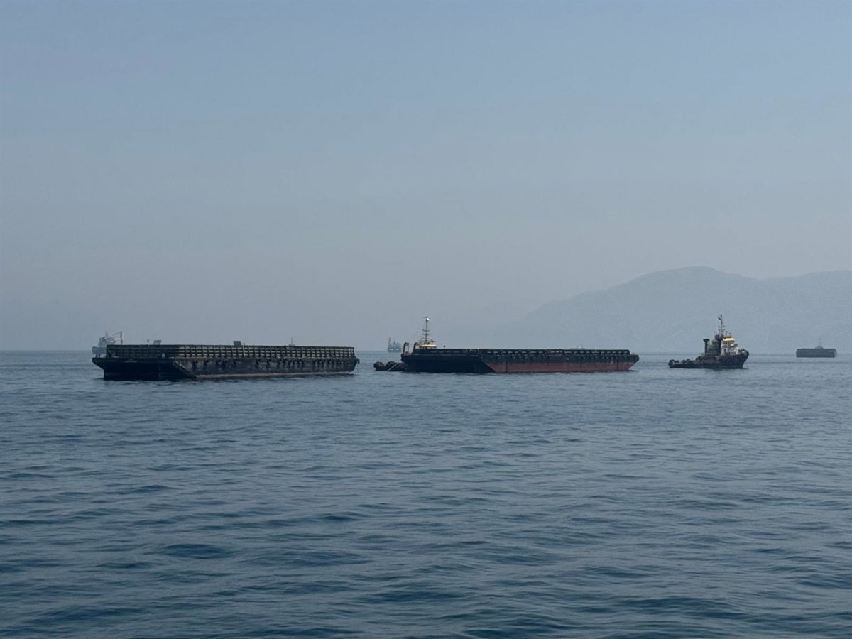 Barcos en el estrecho de Ormuz con bandera de Irán al fondo
