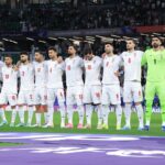 Jugadores de fútbol de Irán en un estadio con banderas oficiales
