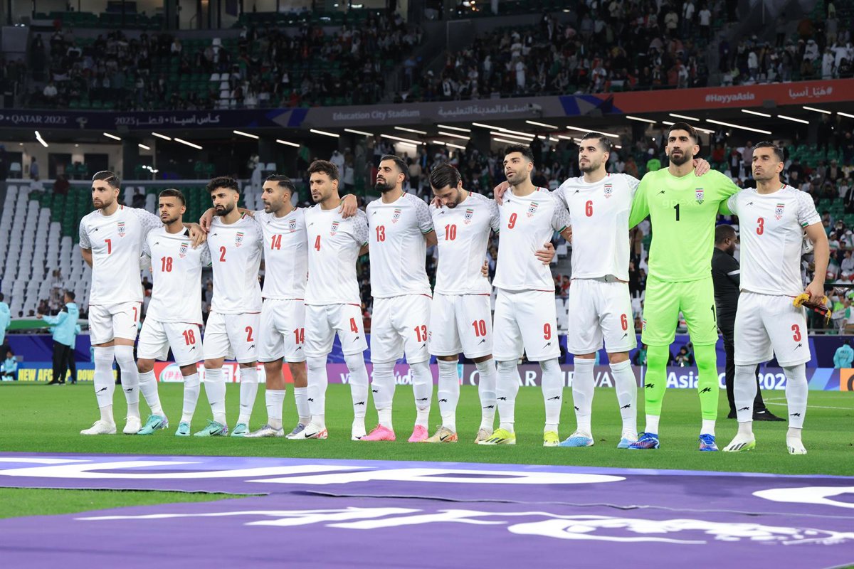 Jugadores de fútbol de Irán en un estadio con banderas oficiales