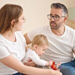 Imagen de una pareja discutienedo de forma constructiva con un niño en el fondo