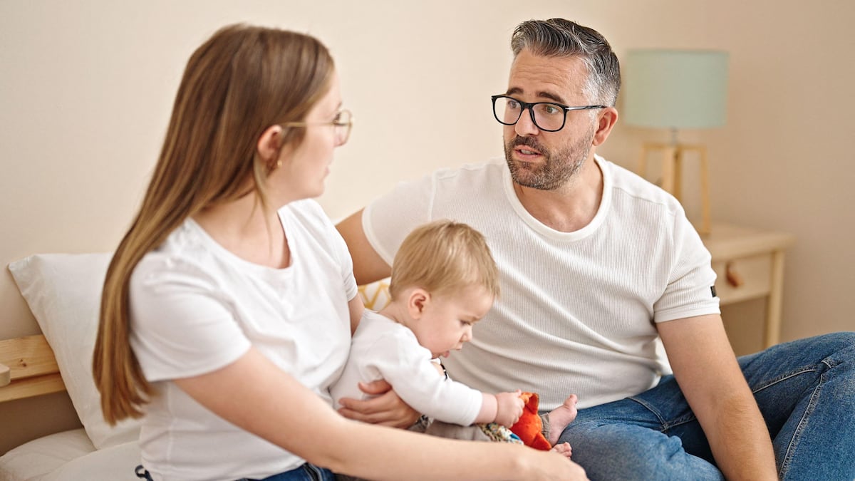 Imagen de una pareja discutienedo de forma constructiva con un niño en el fondo