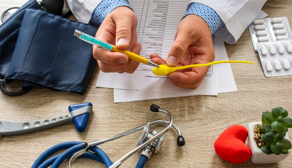Un hombre y una mujer sosteniendo una prueba de embarazo positiva, con un fondo de un consultorio médico