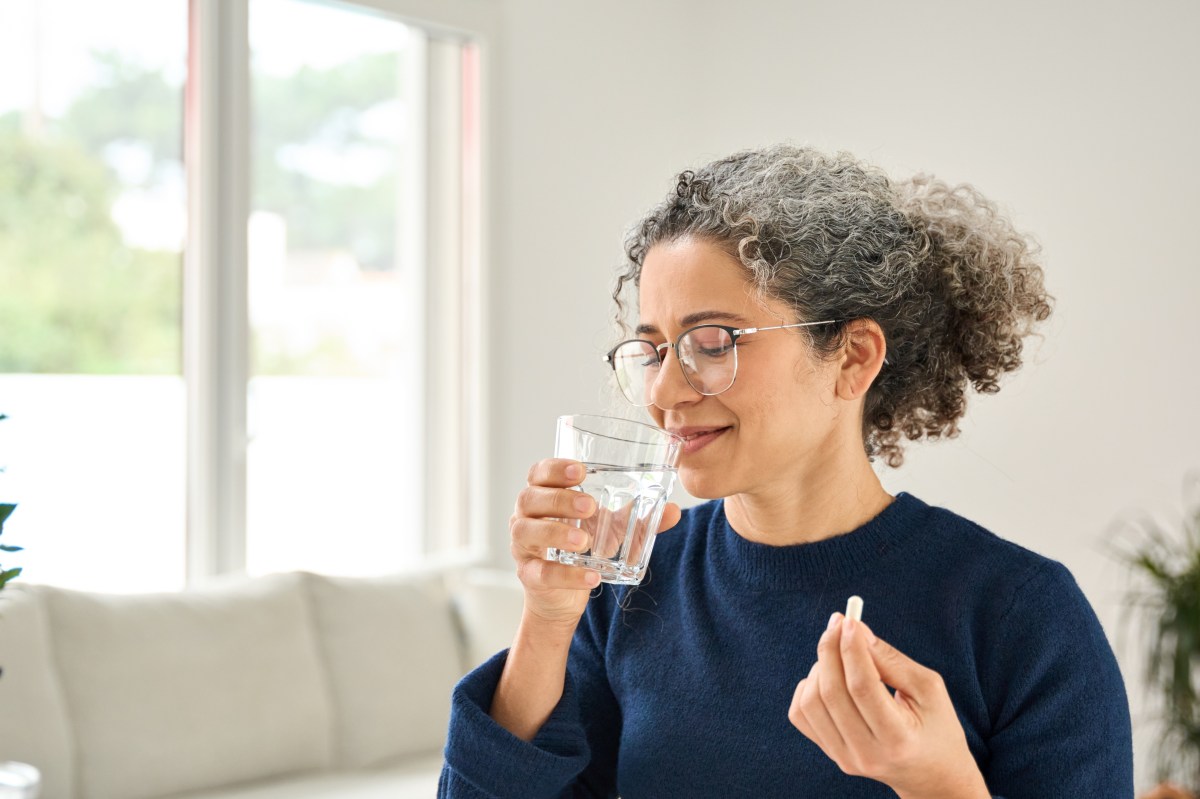 Suplementos de vitamina D, B12, B6, calcio y Omega-3 sobre una mesa con alimentos saludables