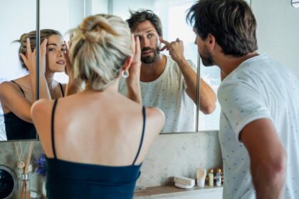 Mujer frente a un espejo analizando su reflejo en un entorno de belleza contemporánea