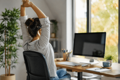 Persona trabajando frente a una computadora tomando una pausa activa para estirarse